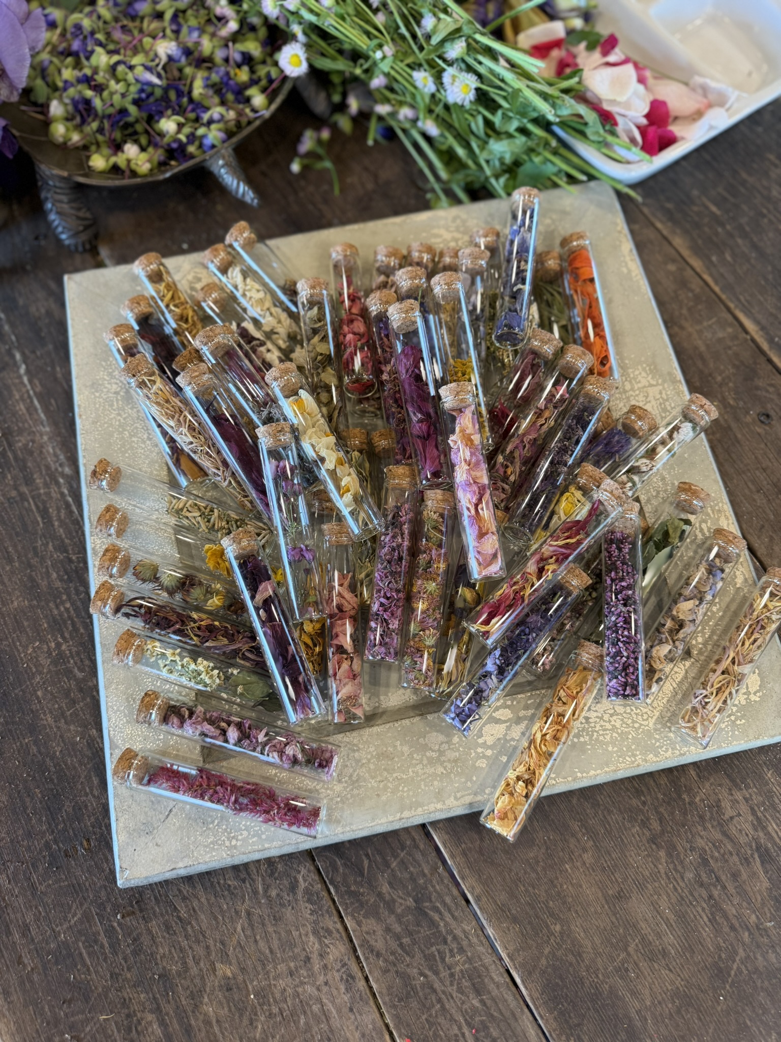 Corked vials fanned across a gilded tray, each filled with a different botanical color