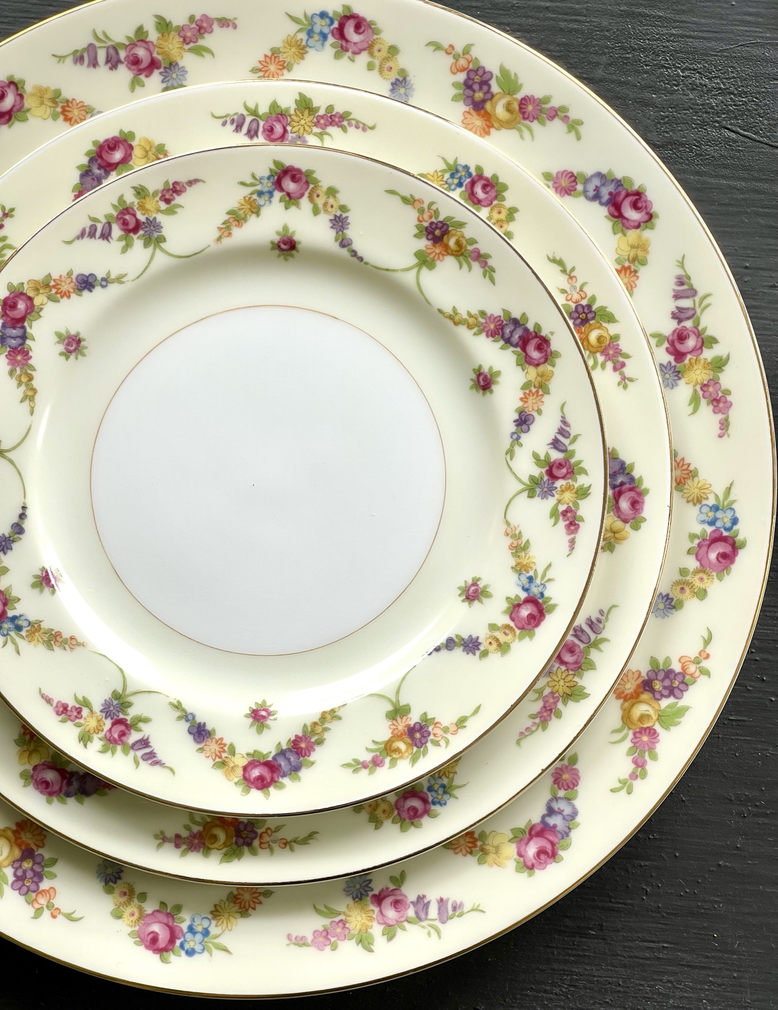 The Duchess pattern — a continuous garland of roses, peonies, bluebells and forget-me-nots running all the way around cream plates in three sizes