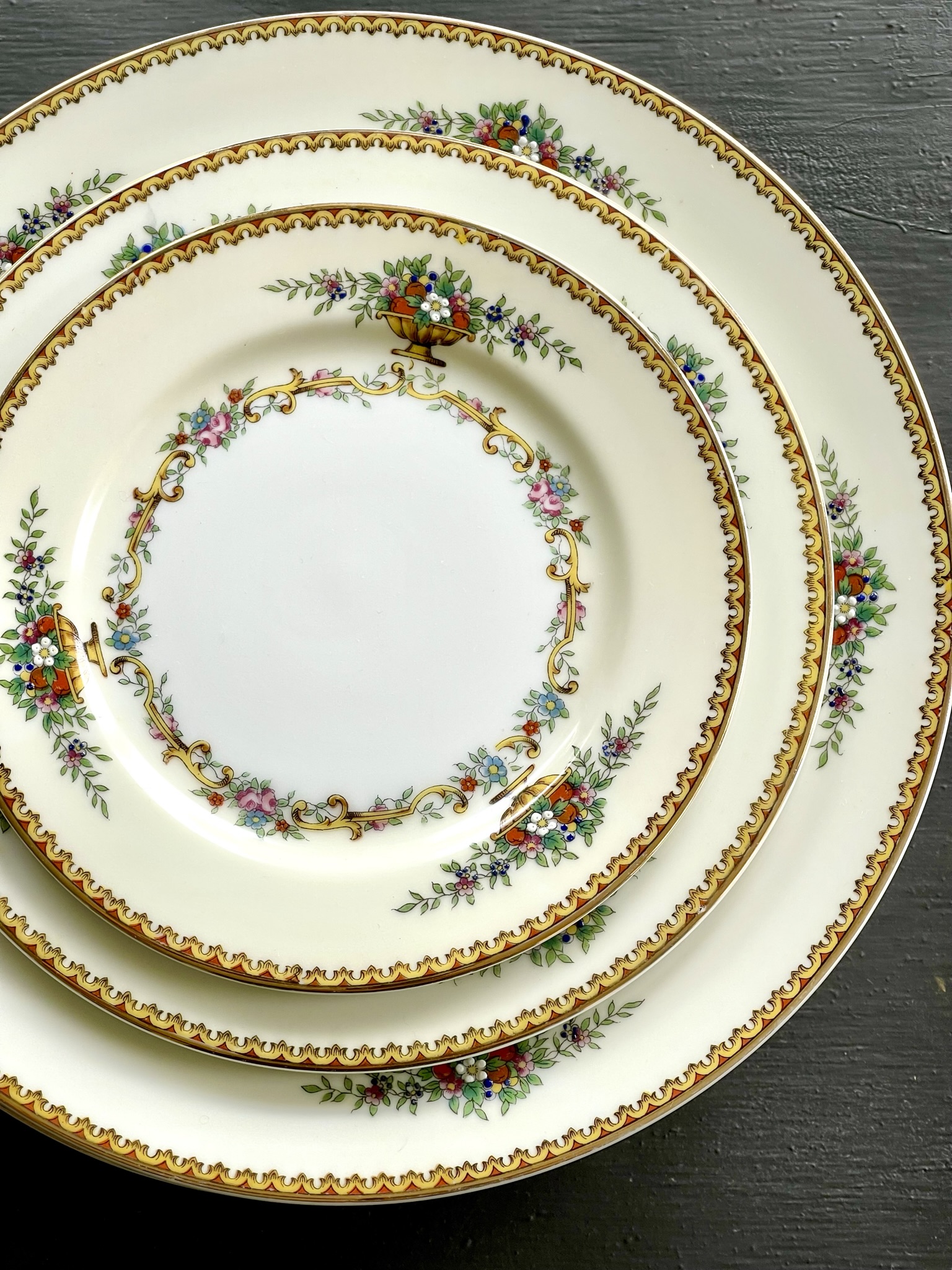 Romola by Noritake — cream plates with an elaborate gold-scallop border carrying urn motifs and small flower swags, inner band with garlands of pink roses