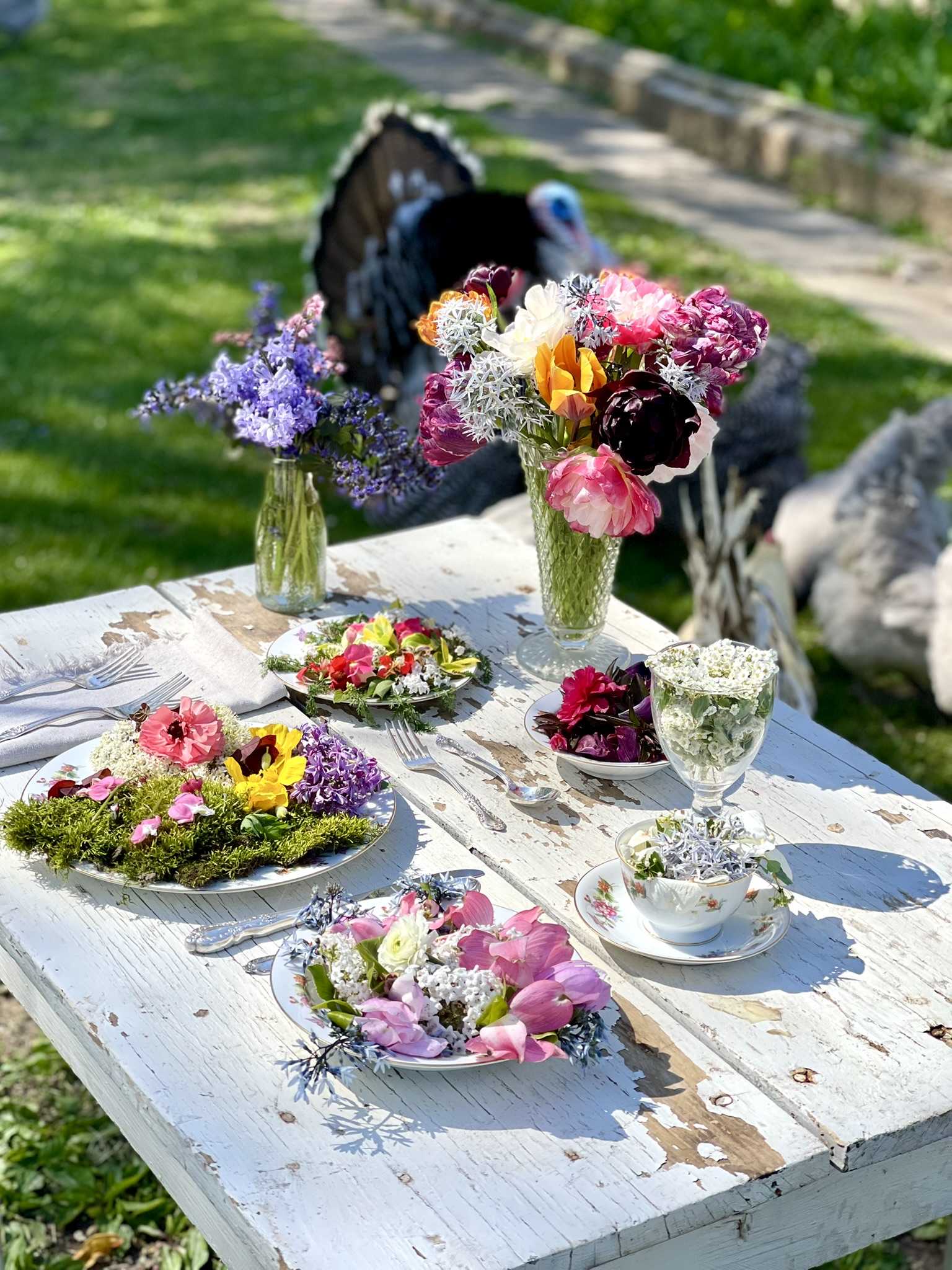 A tom turkey in full display behind the flower-filled table, his fan spread wide