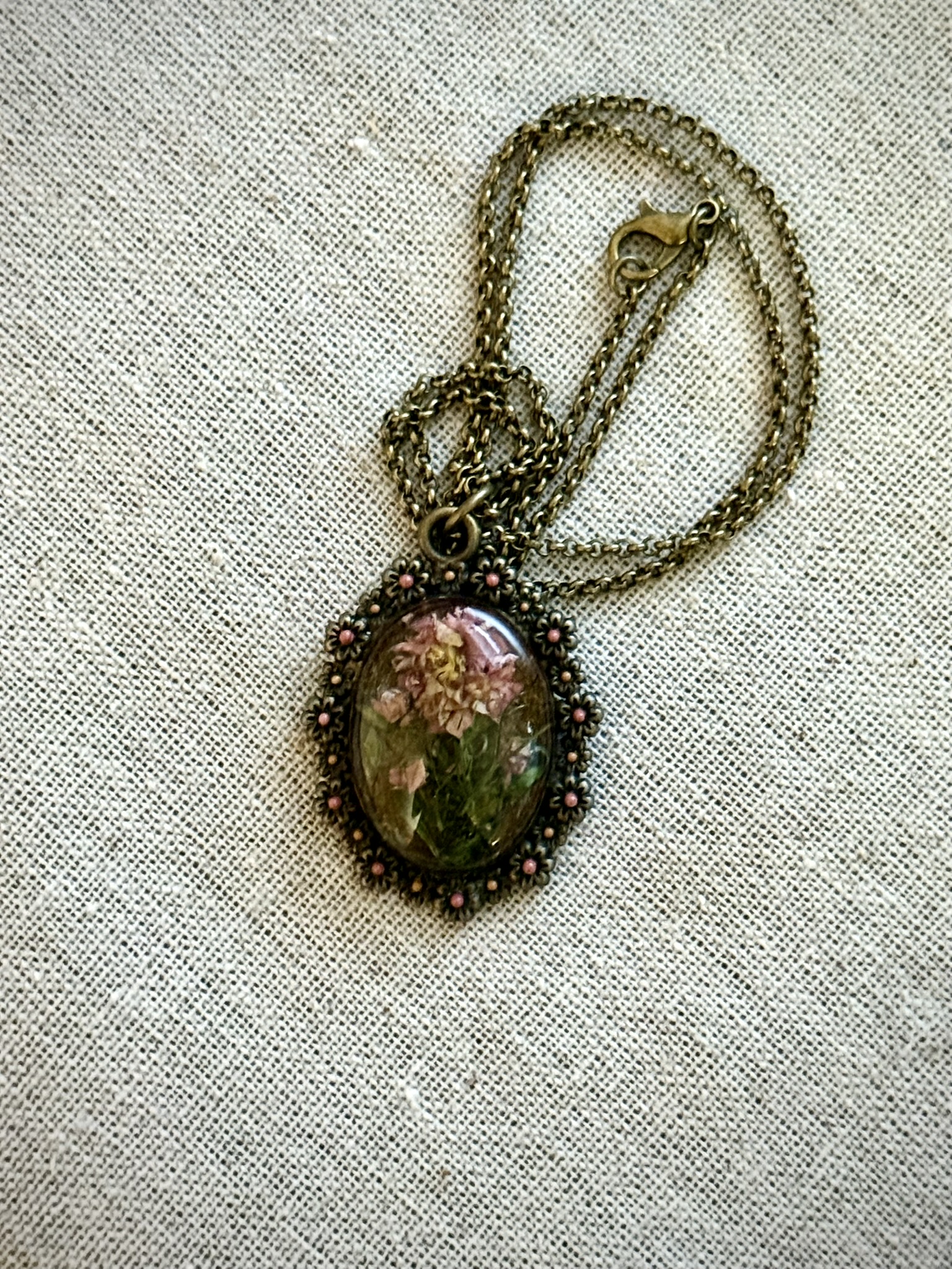 Ornate oval filigree pendant with pink bead accents, pink botanical and green fern in resin