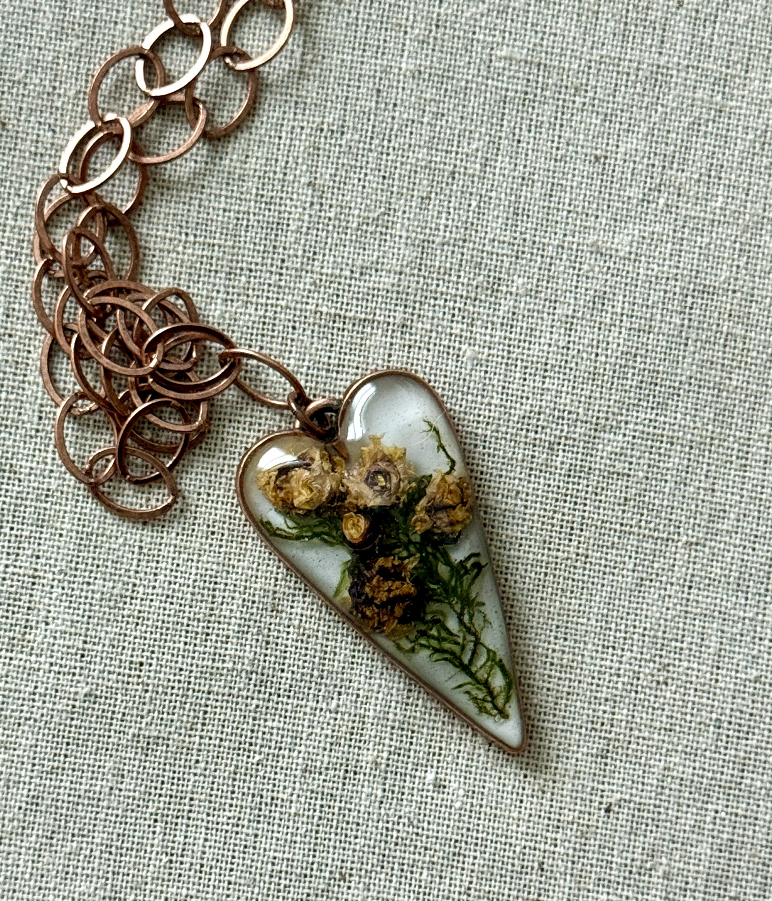 Elongated heart pendant with golden dehydrated lily-roses on copper chain