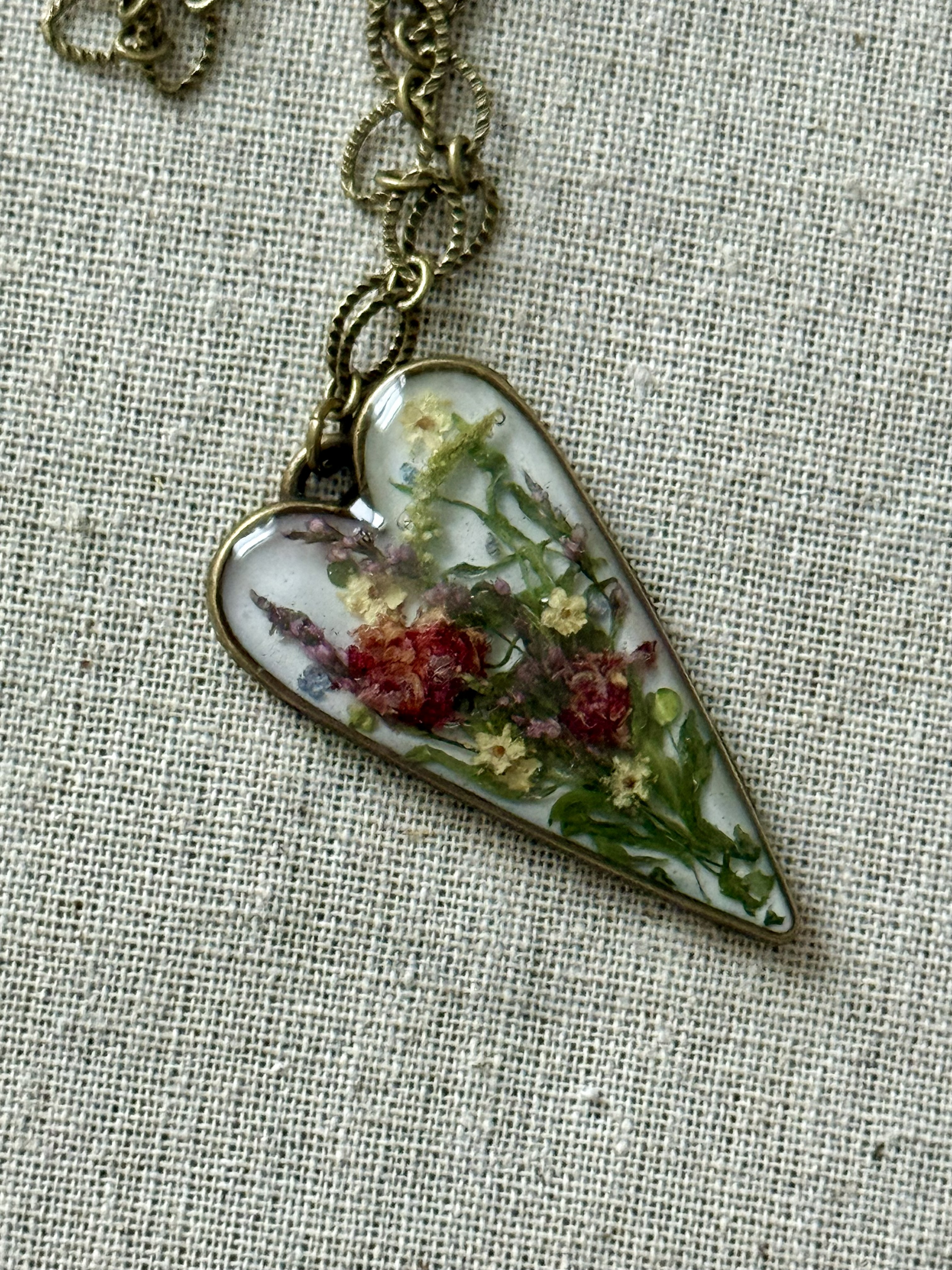 Elongated heart pendant with miniature bouquet in resin on brass chain