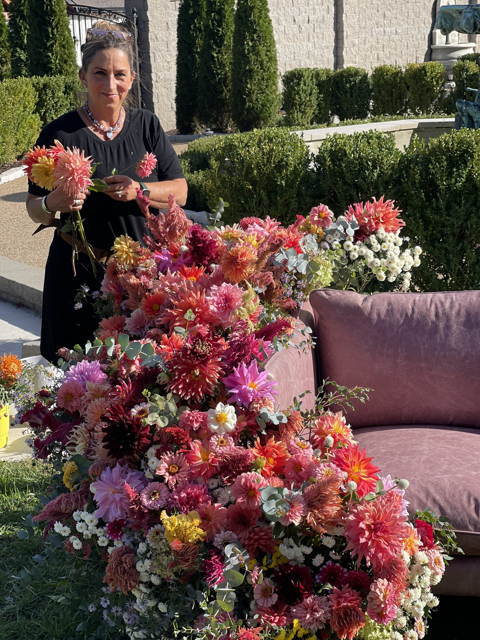 Luli standing back from the completed dahlia armature — hundreds of stems, placed by hand