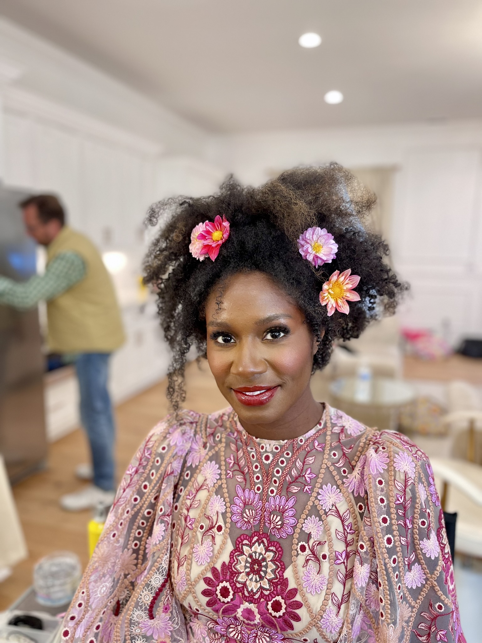 Bride with dahlias tucked into natural Afro hair in the makeup room
