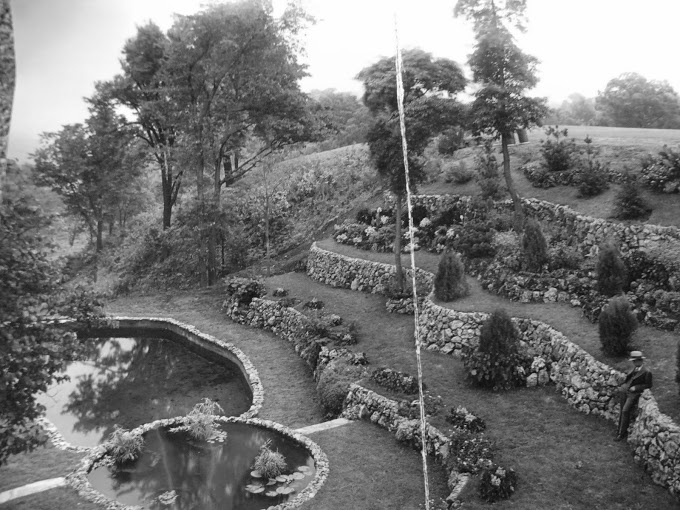 Aerial view of the Sunken Garden — stone terracing descending to the lily pond, one figure visible to show the scale of what was built