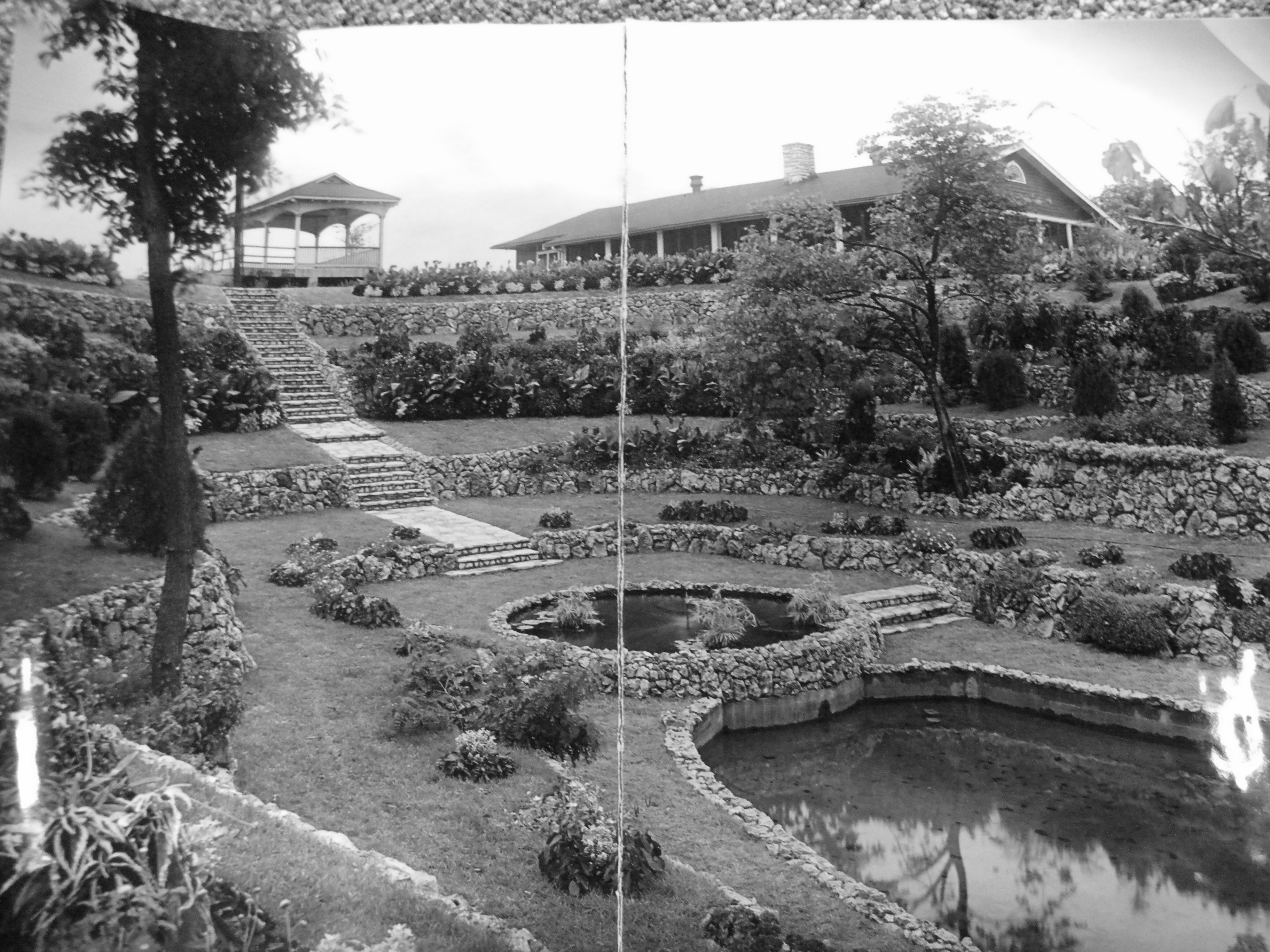 The Sunken Garden in its prime — the full panorama: gazebo upper left, main house on the ridge, grand stone staircase descending to the lily pond, concentric stone terraced beds on every level
