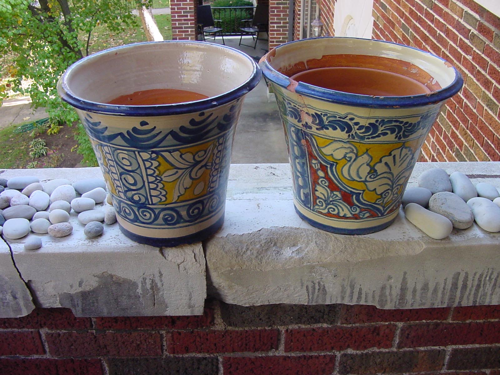 The balcony — two large hand-painted ceramic pots flanking stones arranged along the stone railing