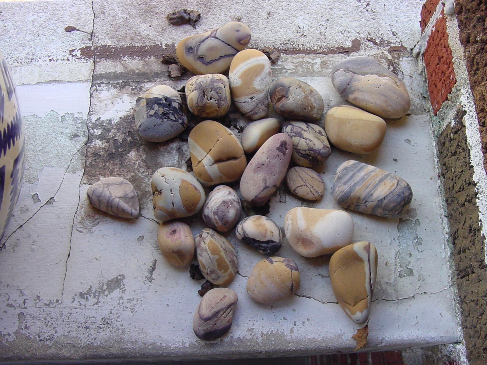 Close view of the balcony stones — warm honey, lavender-grey, and white stones with purple veining, laid out on the stone ledge