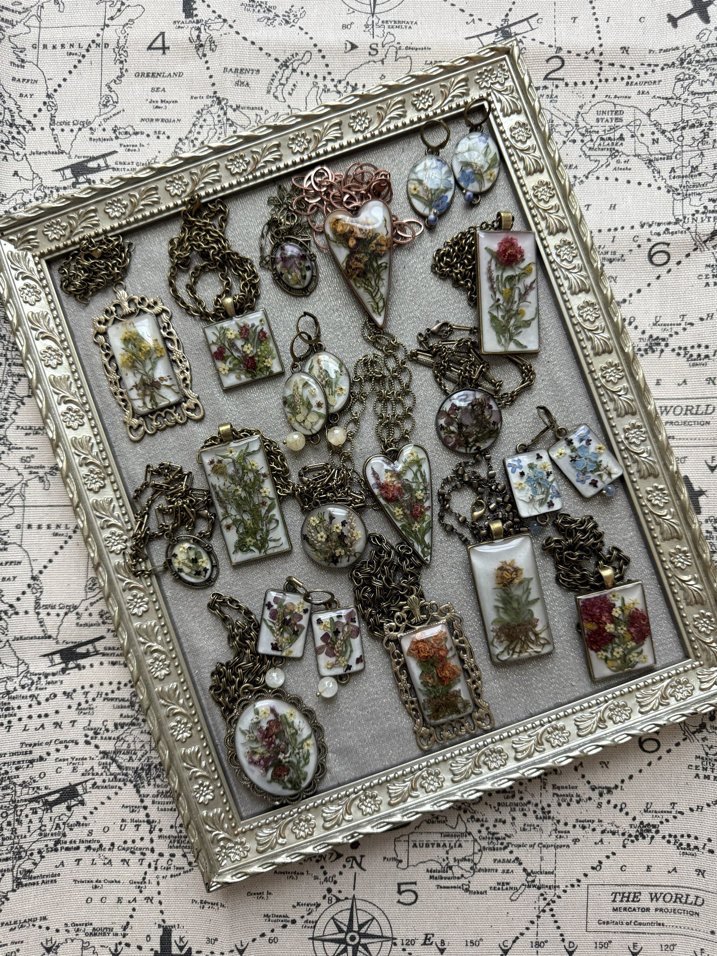 Floral Alchemy Sacred Hearts collection in an ornate silver frame on antique world map fabric