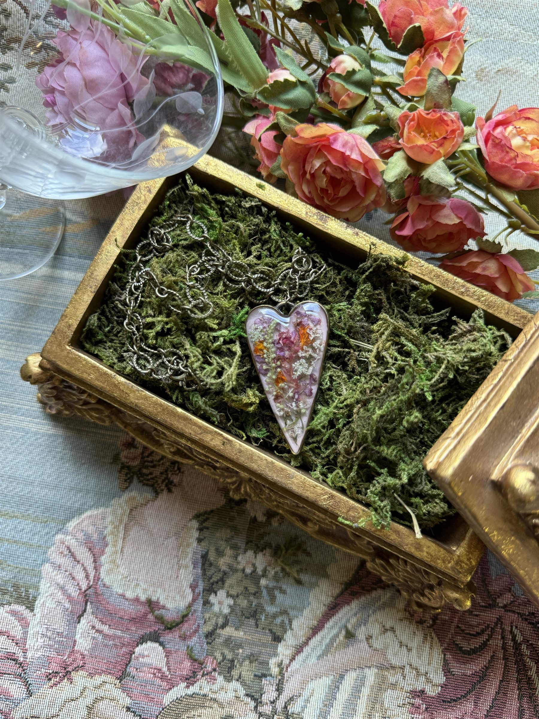 Love, Love, Love — a Sacred Heart pendant in a gold box lined with moss, roses surrounding it — Floral Alchemy